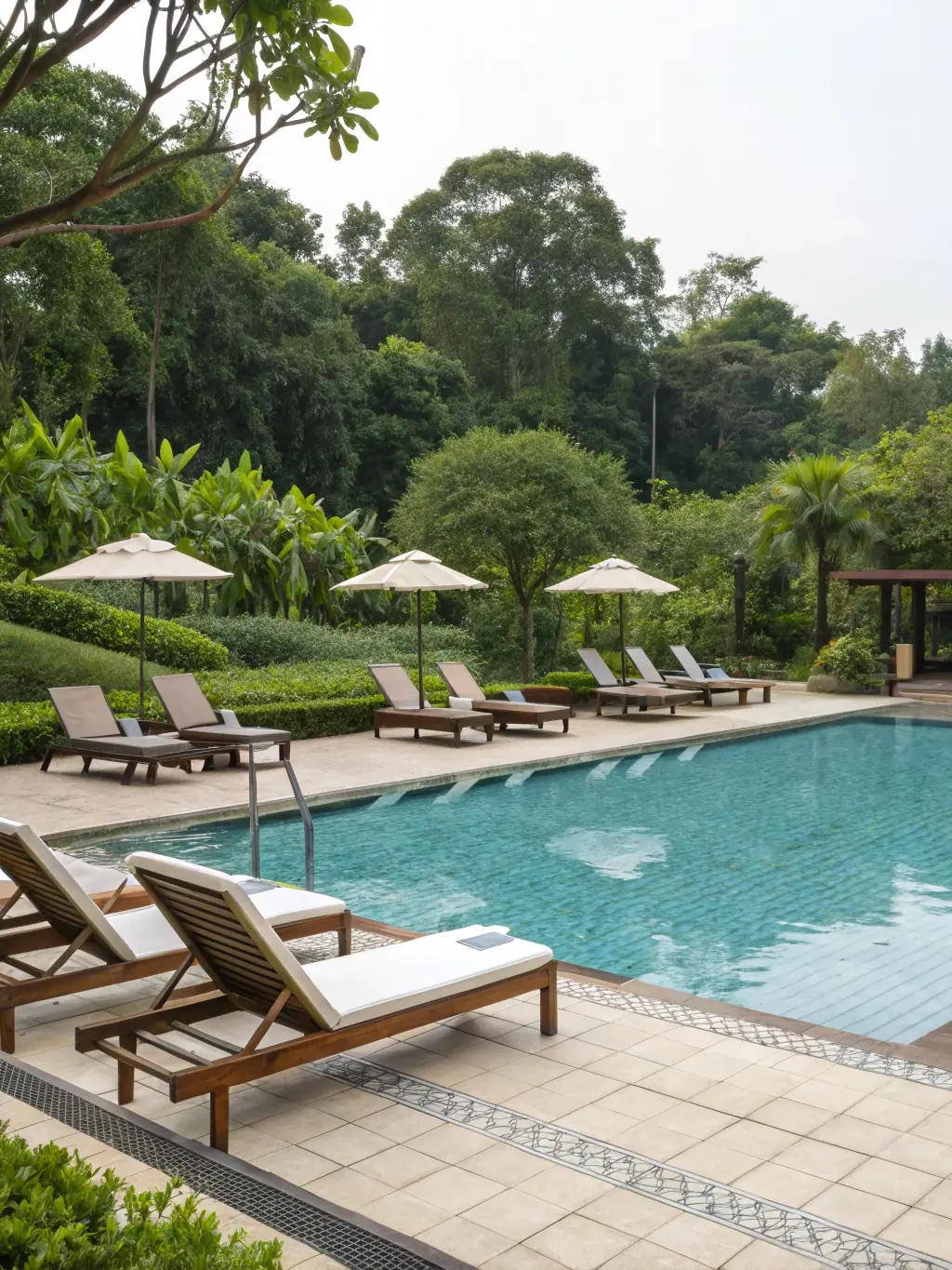 A luxurious swimming pool with a stone deck and clear blue water, surrounded by lush landscaping and comfortable seating.
